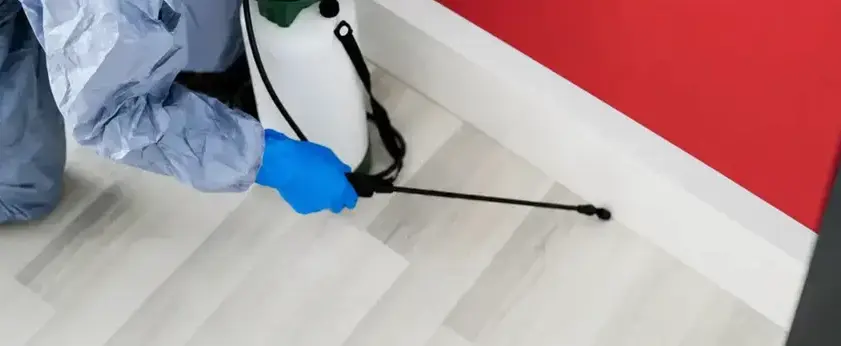 Oakley Pest Control technician applying cockroach treatment along a baseboard in a Manteca, CA home